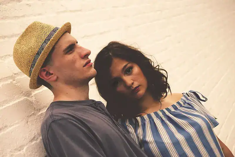 ein nachdenklicher Mann, der neben verwirrter Frau neben weißer Wand steht