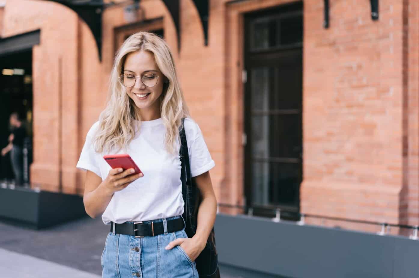 frau laechelt mit handy in hand