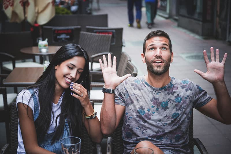 junger Mann lacht mit Mädchen im Café