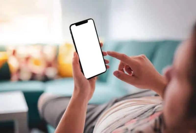 11 tegn på at han holder mulighetene åpne Mann, der auf der Couch liegt und Telefon ansieht