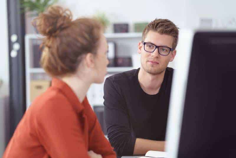 11 tegn på at han holder mulighetene åpne junger Geschäftsmann beim Treffen, der Kollegen mit nachdenklichem Ausdruck zuhört