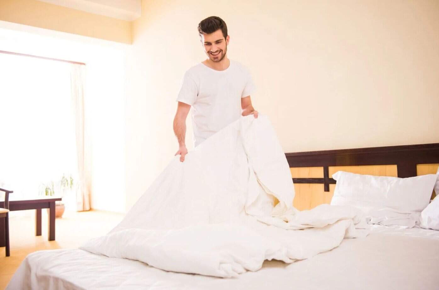 Lächelnder Mann, der morgens das Bett macht