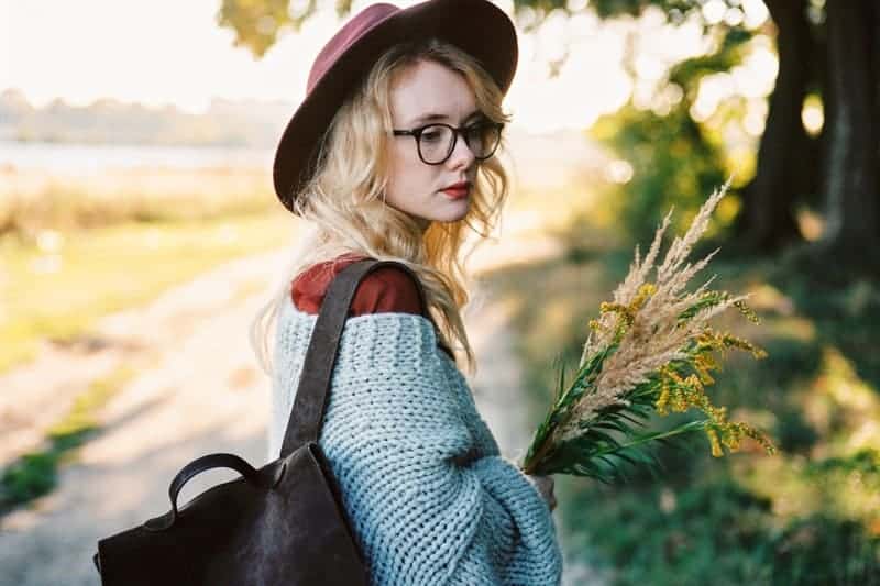 Eine Frau mit Hut hält Blumen