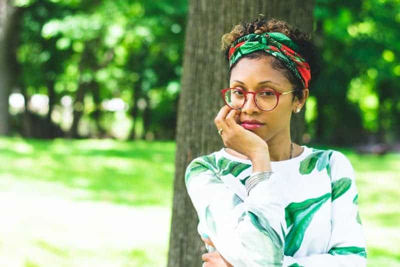 Frau hält ihren Bart an Baum gelehnt