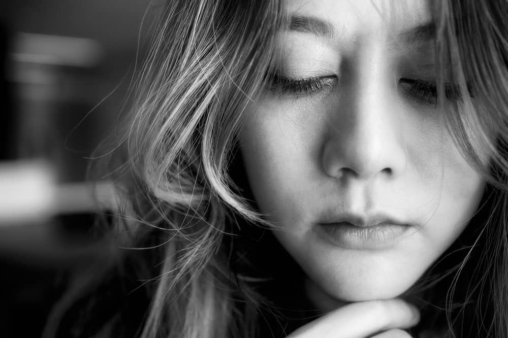 ein Porträt einer traurigen Frau mit geschlossenen Augen