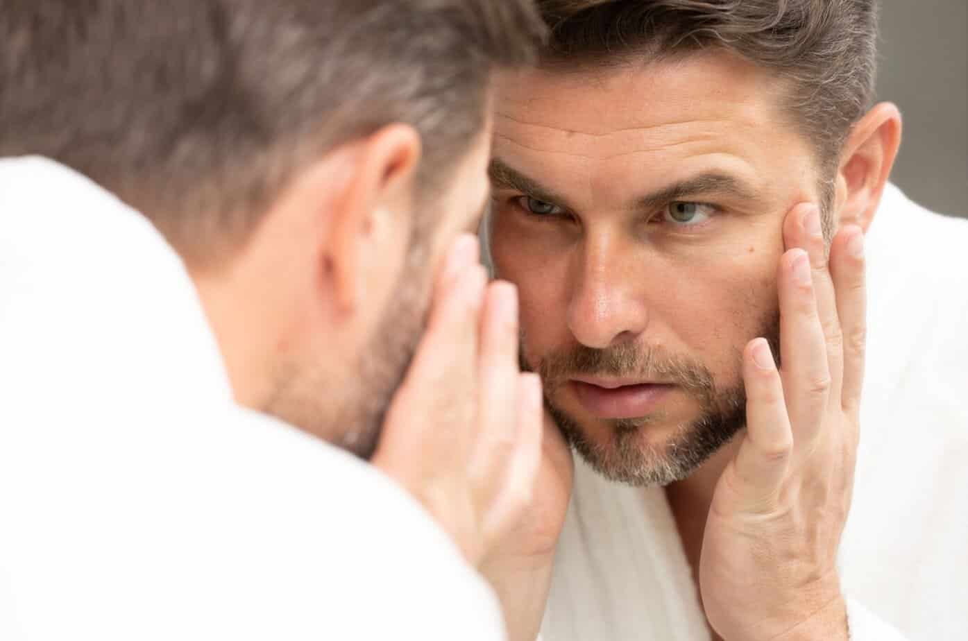 mann betrachtet sich im spiegel