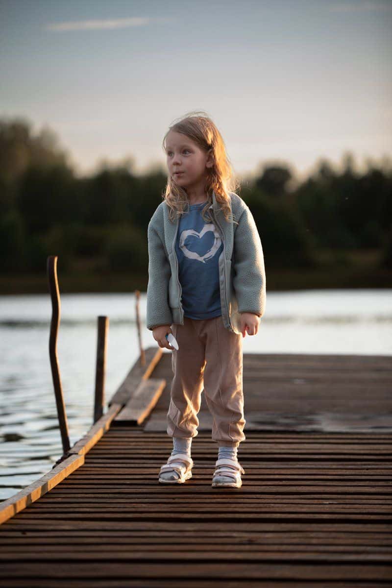 A little girl crouching on a dock near a lake · Free Stock Photo A little girl crouching on a dock near a lake · Free Stock Photo