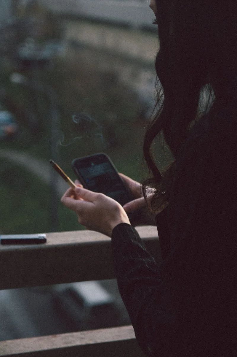 Woman Using Cellphone and Holding a Cigarette · Free Stock Photo