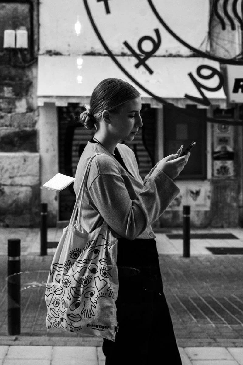 Black and White Shot of a Woman Checking her Smartphone in the Street ·  Free Stock Photo