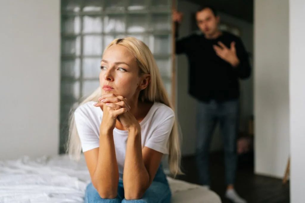 Hva får gifte menn til å søke tilflukt hos en annen kvinne? 6 sjokkerende grunner Ein Mann steht in der Tuer, waehrend eine Frau auf der Couch sitzt