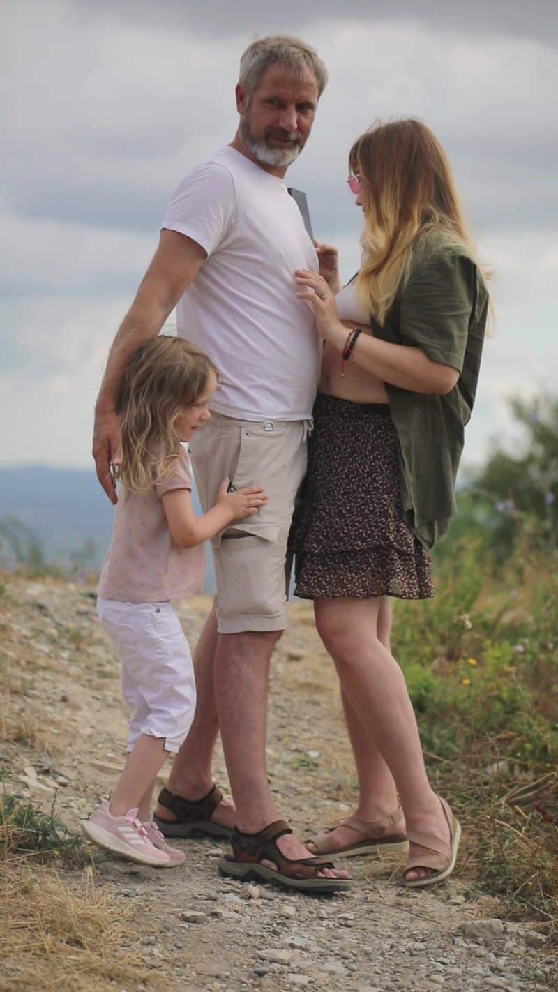 A family standing on a dirt road with a sign that says, the best way to raise a child A family standing on a dirt road with a sign that says, the best way to raise a child