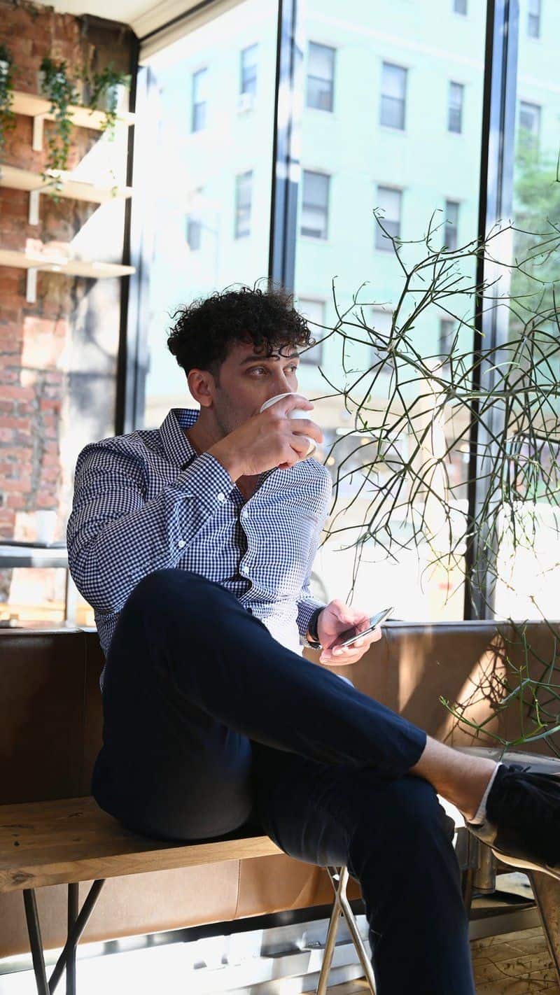 A Man Drinking Coffee while Holding a Cellphone A Man Drinking Coffee while Holding a Cellphone